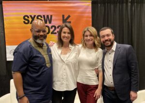 Panelists stand in front of the SXSW banner at their panel